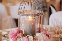 a cage with a candle and pink and white blooms around is a cool idea of a wedding centerpiece