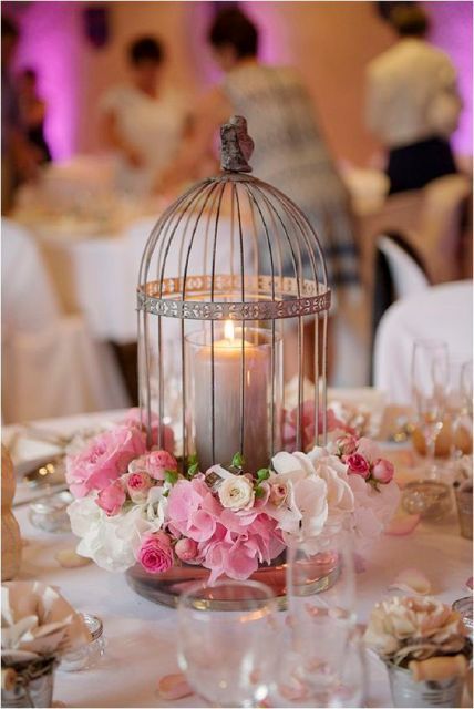 a cage with a candle and pink and white blooms around is a cool idea of a wedding centerpiece