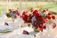 a catchy and bold red and gold wedding tablescape with lush red floral arrangements, red napkins, white porcelain and gold cutlery