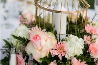 a catchy garden wedding centerpiece of a wreath with pink and white blooms, greenery and a golden cage