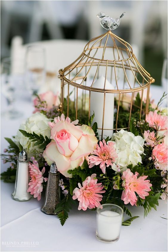 a catchy garden wedding centerpiece of a wreath with pink and white blooms, greenery and a golden cage