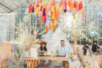a colorful boho wedding backdrop of bright tassels, monograms, pampas grass and a teepee can be DIYed easily