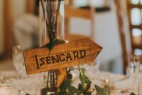 a cool LOTR wedding centerpiece of red roses, vines, pinecones, lights and an Isengard sign and candles around