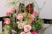 a fantastic wedding centerpiece of a green cage with pink and coral blooms and lots of greenery