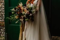 a fantasy bride wearing an A-line wedding dress, a sheer tulle capelet with a hood, carrying a lush wedding bouquet