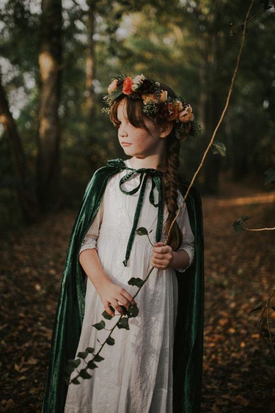 a flower girl styled with a beaded white dress, a green cloak and a floral crown is a lovely idea for a LOTR wedding