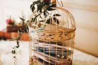 a golden cage with letters and some roses and greenery is a chic idea for a vintage-inspired wedding