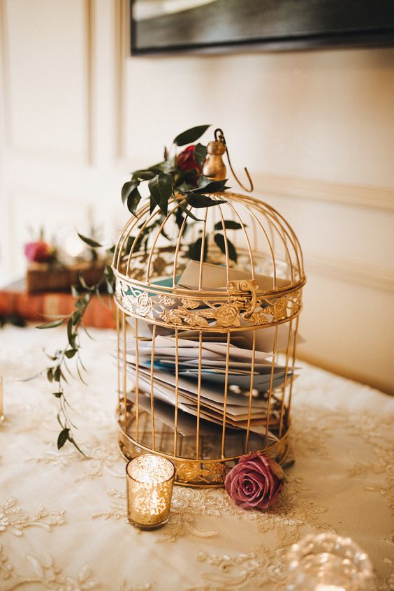 a golden cage with letters and some roses and greenery is a chic idea for a vintage-inspired wedding