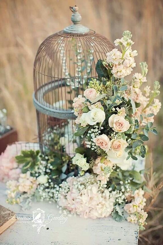 a gorgeous cage decorated with crystals, blush and white blooms and greenery as a refined wedding centerpiece