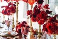 a gorgeous red and gold wedding tablescape with wihte and gold porcelain, tall centerpiece of red and orange bloms and glasses