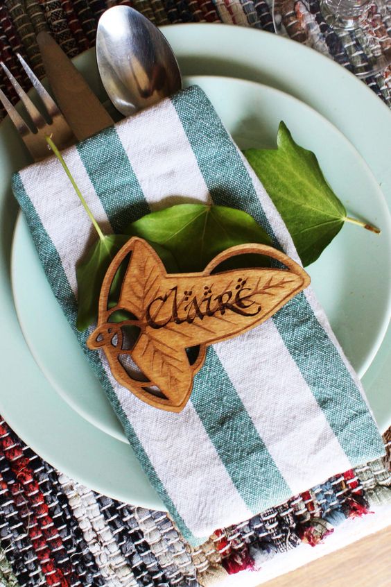 a hobbit place setting with green plates, a striped napkin and a wooden leaf buckle just like in LOTR
