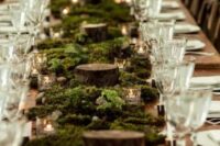 a lovely LOTR wedding reception table with moss, tree slices and candles is a cool idea for a fantasy wedding