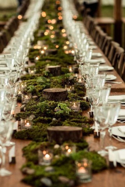 a lovely LOTR wedding reception table with moss, tree slices and candles is a cool idea for a fantasy wedding