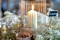 a lovely wedding centerpiece of baby’s breath, cages as candleholders and a chalkboard sign