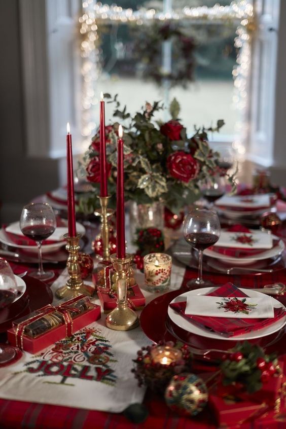 a luxurious wedding tablescape in gold and red, with a red tablecloth and napkins, red candles and roses is adorable