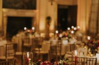a refined and chic wedding tablescape with a lush red and blush wedding centerpiece, tall red candles and white linens