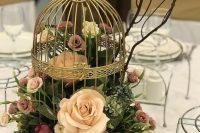 a refined brass cage with blush and mauve roses and leaves is a catchy and chic wedding centerpiece