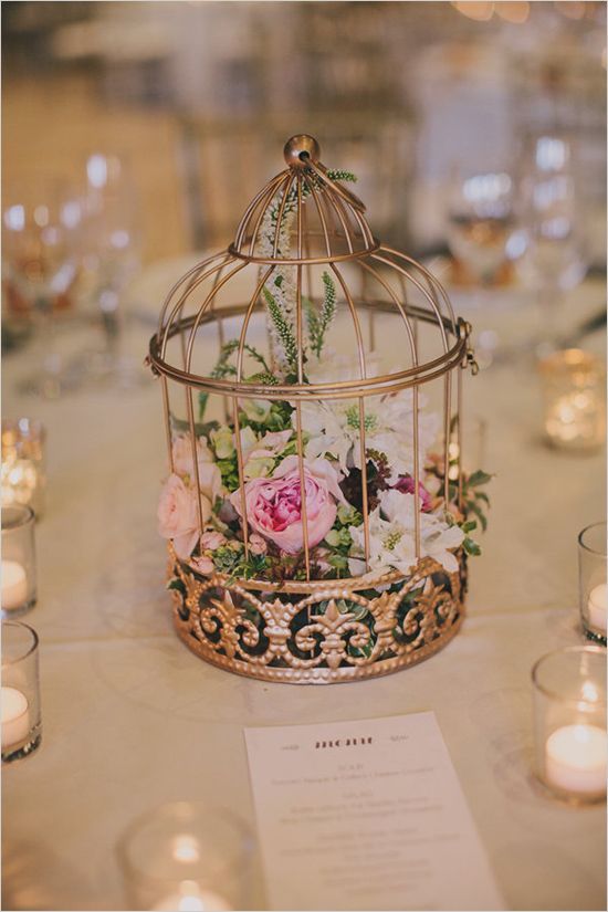 a refined copper cage with white and pink blooms and greenery is a beautiful wedding centerpiece