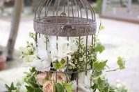 a shabby chic cage with blush and white blooms and greenery is a cool idea for a shabby chic wedding