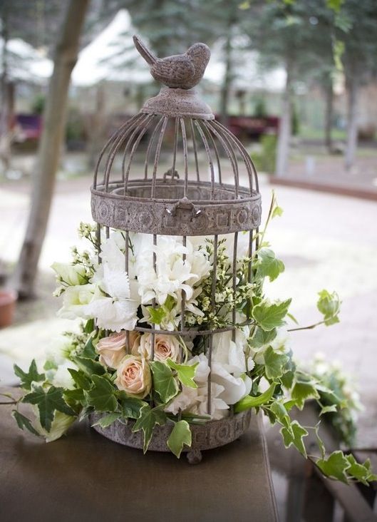a shabby chic cage with blush and white blooms and greenery is a cool idea for a shabby chic wedding