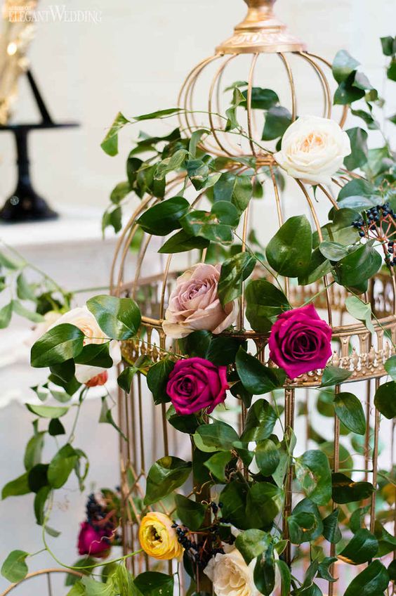 a sophisticated golden cage with pink, fuchsia and yellow blooms and greenery is amazing as a centerpiece