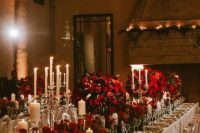 a sophisticated wedding table setting with candles, red blooms and elegant white porcelain is amazing