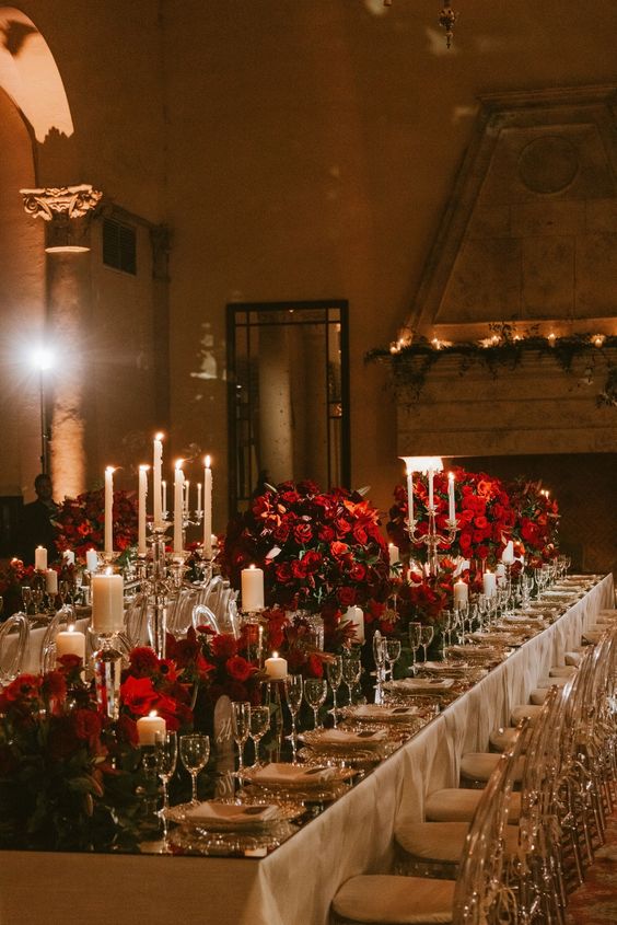 a sophisticated wedding table setting with candles, red blooms and elegant white porcelain is amazing