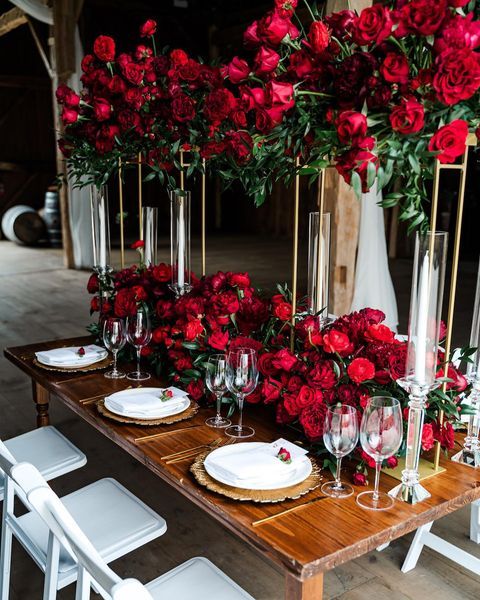 a stylish wedding tablescape with lush red florals, gold chargers and cutlery, candles is a chic and refined solution