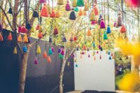 a wedding space decorated with lots of colorful tassels is a fun and cool idea for outdoors and indoors, make them yourself