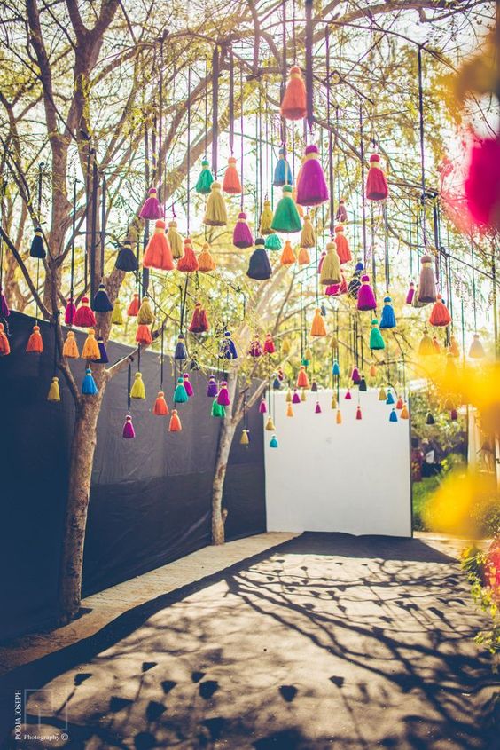 a wedding space decorated with lots of colorful tassels is a fun and cool idea for outdoors and indoors, make them yourself