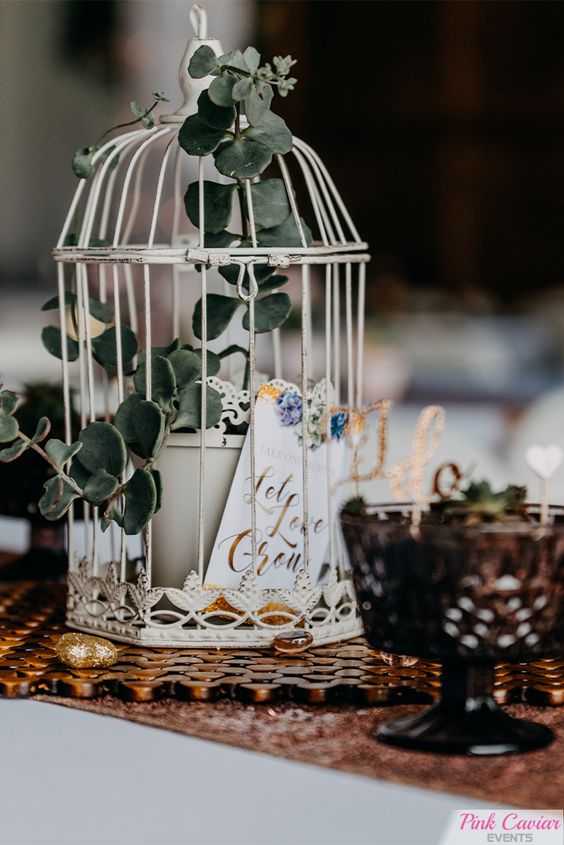 A white cage with a potted plant and a card is a cool and very budget friendly decor idea