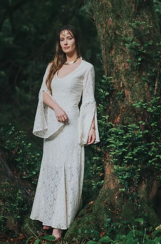 an Elvish bride wearing a lace wedding dress with bell sleeves and a V-neckline, a statement necklace and a headpiece