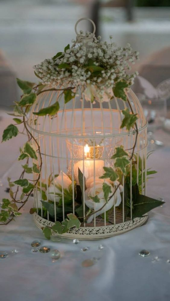 an exquisite white cage with white blooms and a candle plus some baby's breath on top is amazing