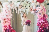 an ombre wedding arch decorated with white, light pink and fuchsia balloons, blooming branches and matching tassels is amazing