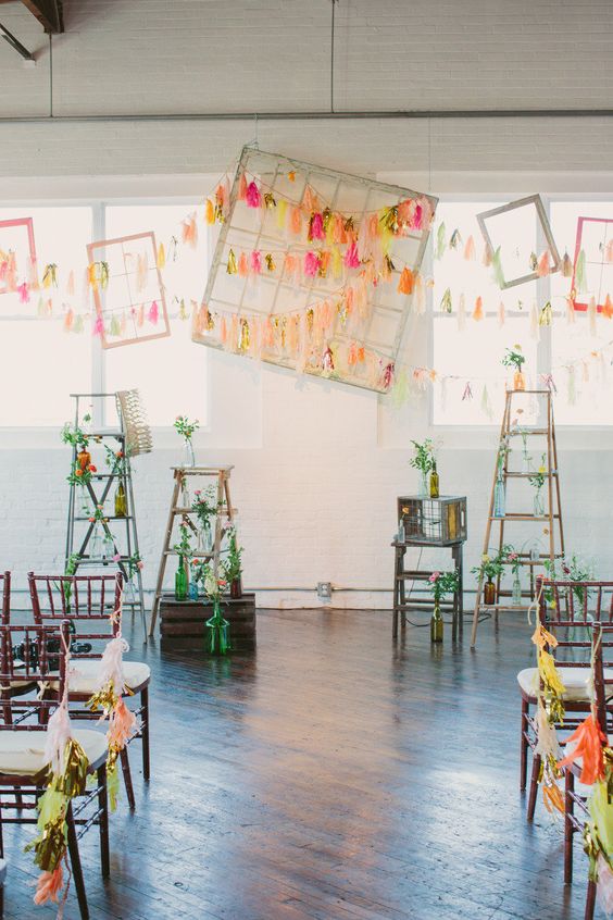 bright and colorful tassel garlands and empty frames are a creative and simple wedding backdrop that you can DIY