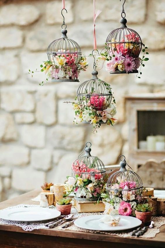 mini cages suspended and on the table with pink and neutral blooms and greenery for a vintage wedding