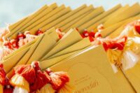 mustard-colored wedding programs with colorful tassels are lovely for a modern playful or boho wedding, they will add color and interest