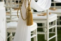 white fabric and oversized gold tassels with rope are an amazing way to accent the wedding aisle without any blooms at all