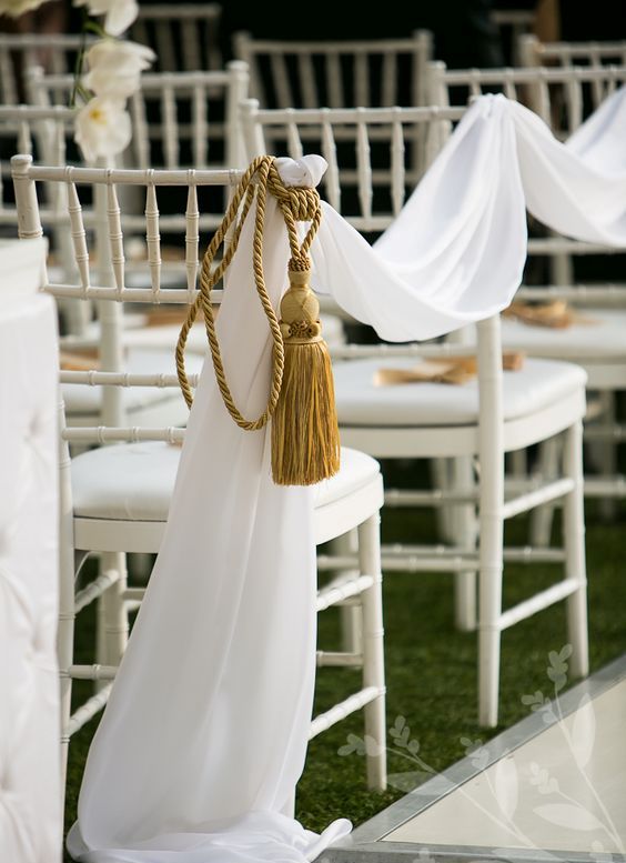 white fabric and oversized gold tassels with rope are an amazing way to accent the wedding aisle without any blooms at all