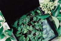 04 a black velvet box filled with greenery and with an acrylic invite on top looks very refined yet modern