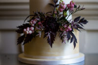 06 The wedding cake was done in ivory and gold, with blooms, dark foliage and berries