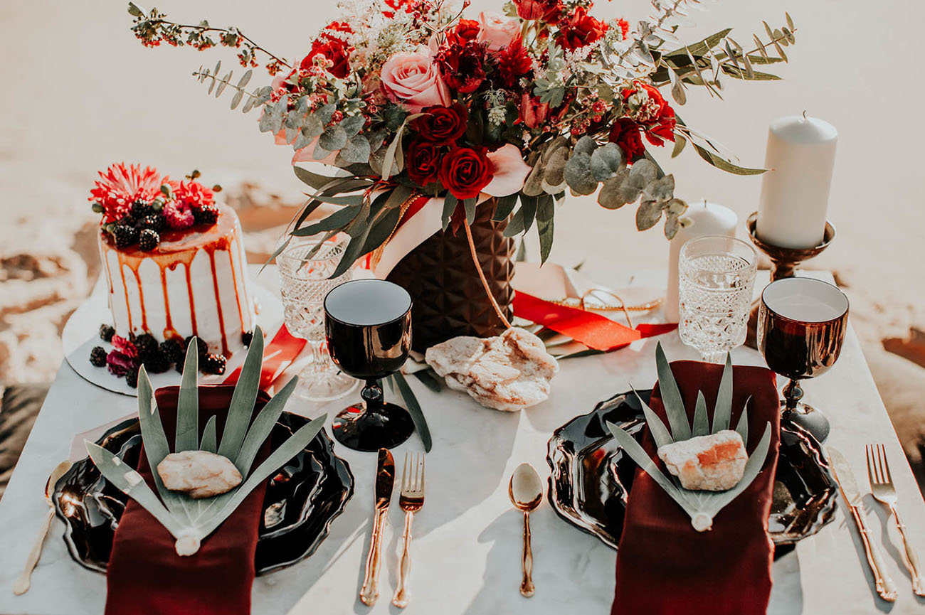 The desert picnic table was set with black plates, large leaves, gold cutlery and black goblets