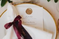 07 a chic tablescape with gold rim plates, greenery and napkins with burgundy bows
