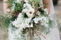 a neutral bouquet with white blooms, evergreens, foliage and pinecones
