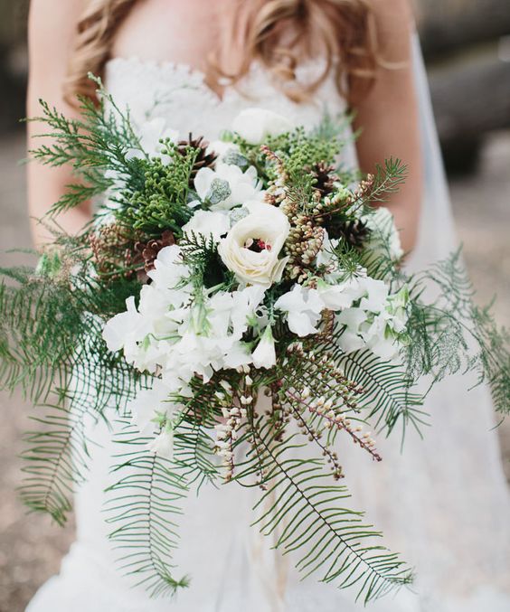 a neutral bouquet with white blooms, evergreens, foliage and pinecones