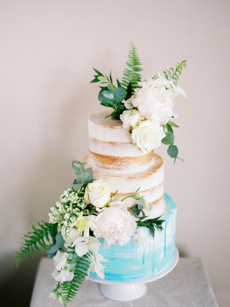 The naked wedding cake had a blue layer and neutral blooms and greenery to match the shoot
