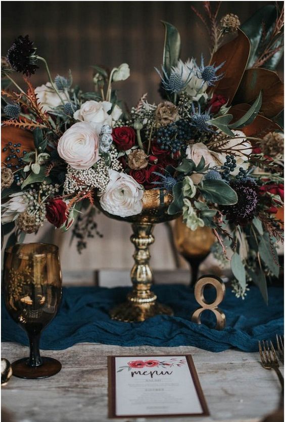a lush textural wedding centerpiece with privet berries, thistles, blush and red blooms and leaves