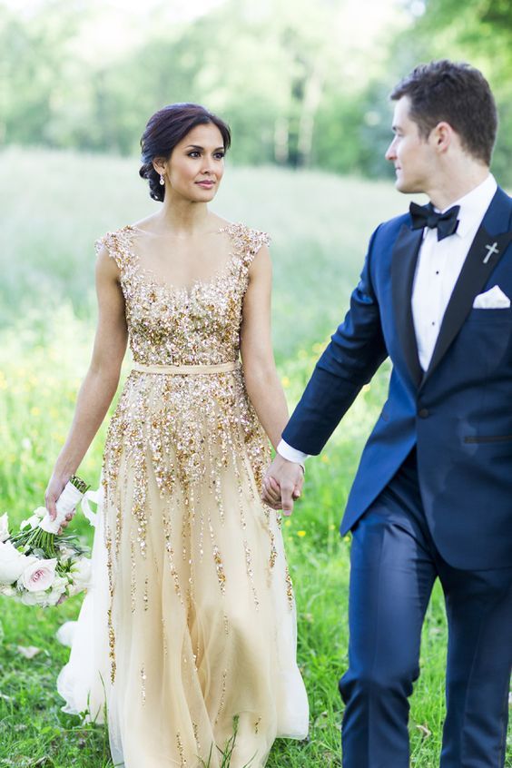 the groom in a navy suit with a bow tie and the bride in a gold glitter wedding gown
