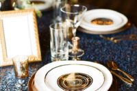 11 a navy sequin tablecloth, gold cutlery, chargers and candle holders for an elegant setting