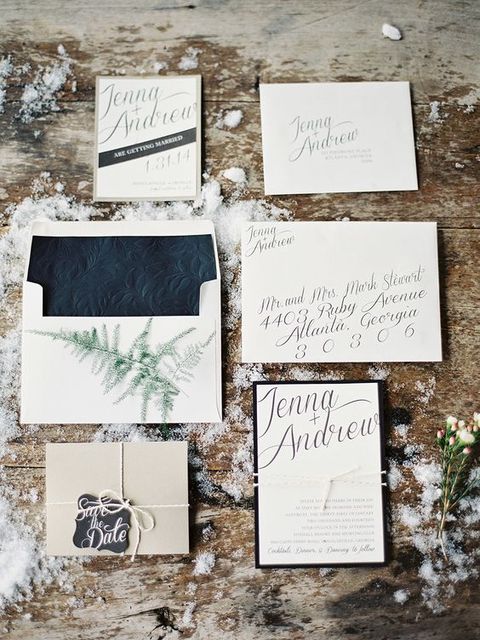 a neutral wedding invitation set with textural black lining, evergreens and black framing